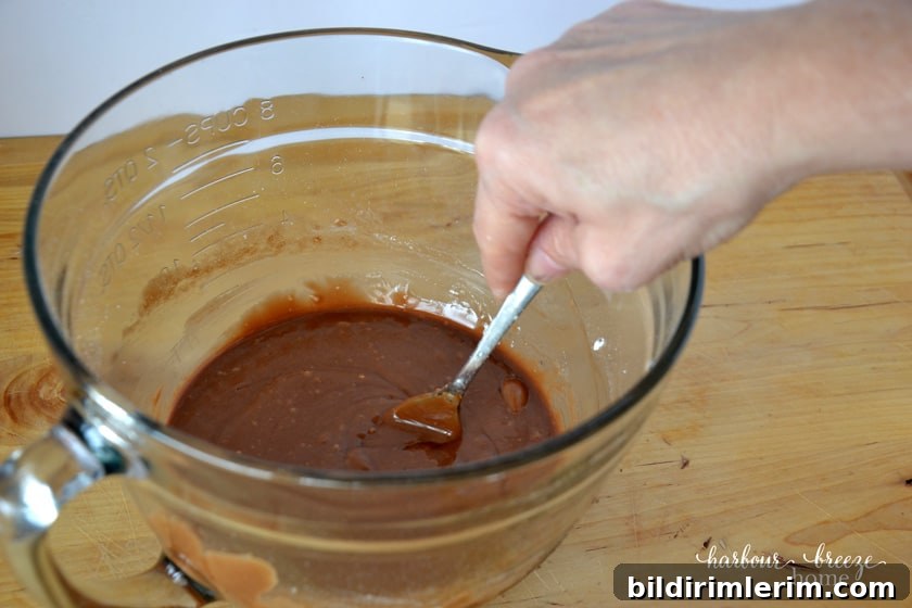Stirring together the melted chocolate and powdered sugar in a bowl to make church window cookies.