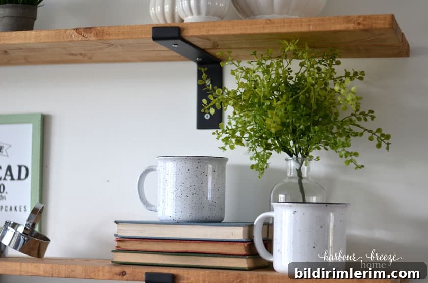 Winter Shelf Decorating Ideas: Proven Styling Tips 7 Two farmhouse enamel mugs sitting on a pile of books with greenery behind.