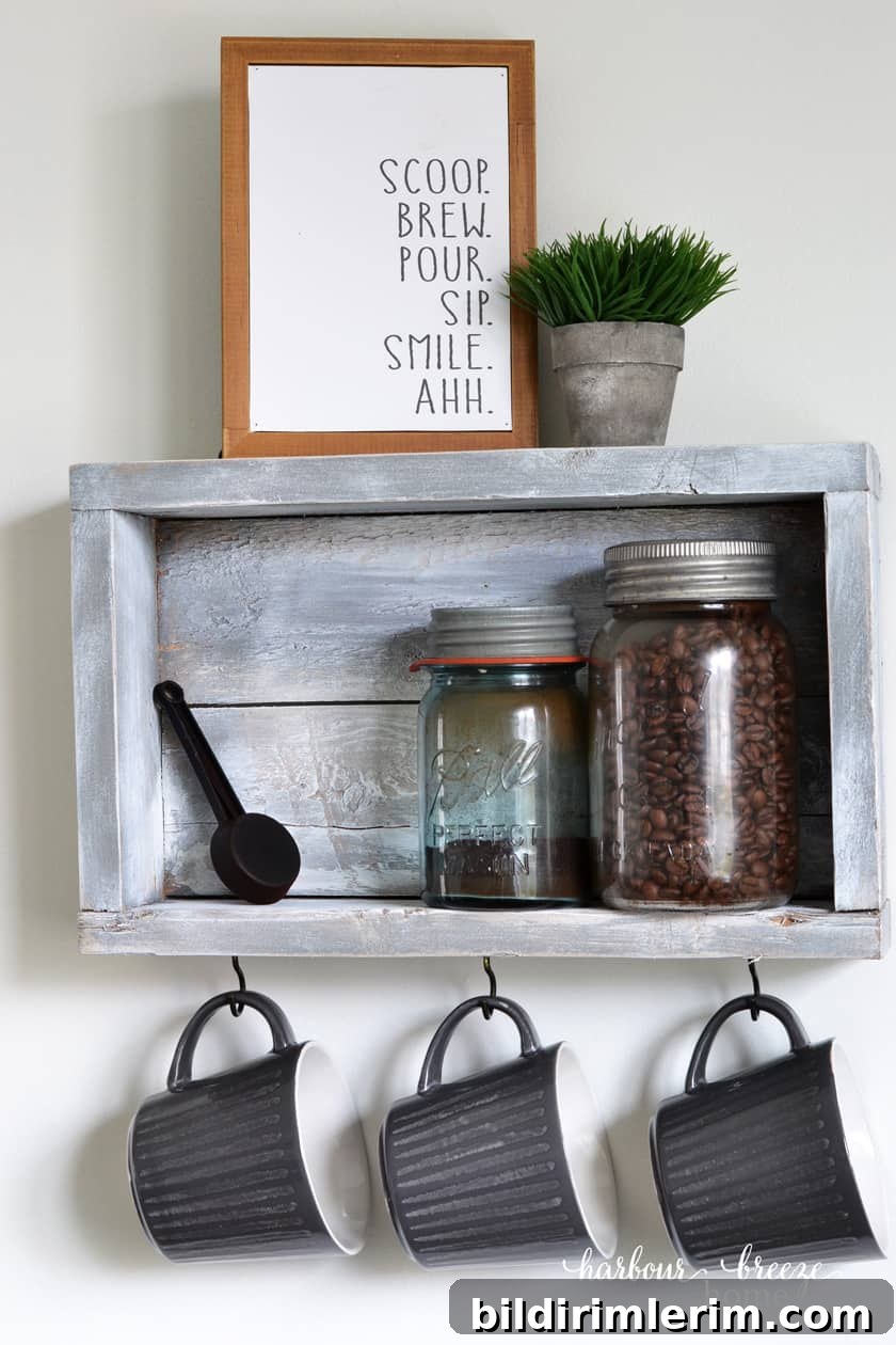 Rustic wall shelf with 3 hooks holding coffee cups and on the shelf is sitting antique mason jars with coffee beans in it.
