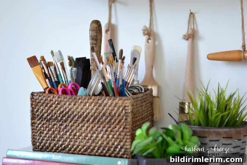 Basket of paintbrushes with greenery beside it