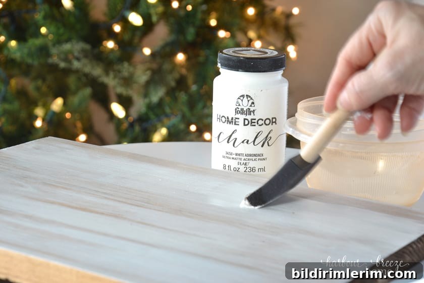 How to Make a Wood Slice Christmas Tree Sign 4 Painting a piece of wood in preparation to make a diy christmas wood sign with a wood slice christmas tree on it.