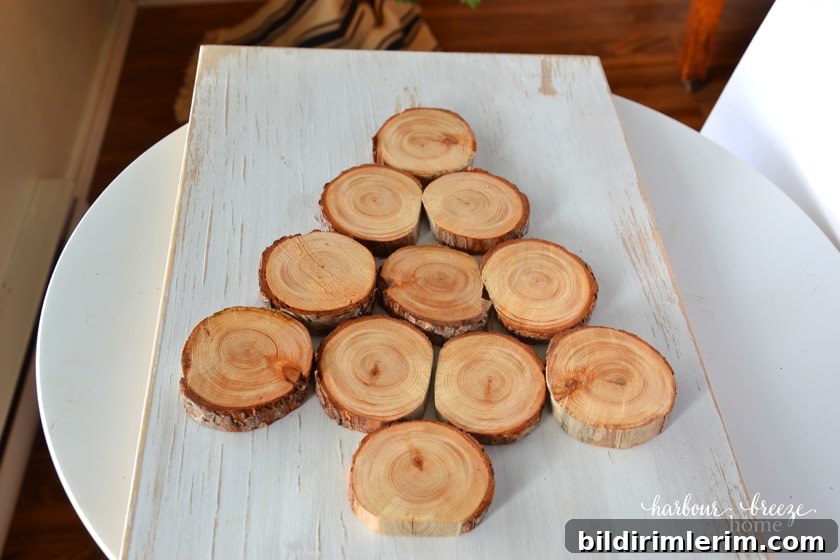 How to Make a Wood Slice Christmas Tree Sign 6 Wood slices arranged on a piece of painted wood to form a Christmas tree shape.