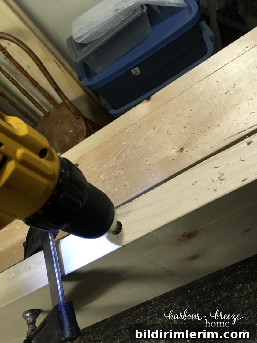 A drill drilling into the DIY floating shelf to make room for the dowel that will be inserted into it.