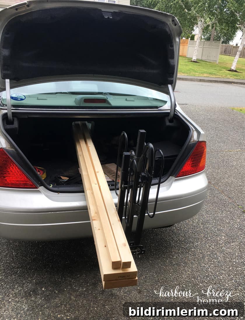 Trunk of car with boards hanging out the back for DIY floating shelves.