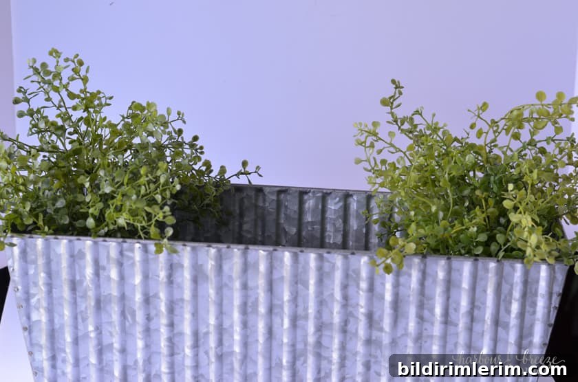 Start filling the centerpiece flower boxes by putting the wispy faux greenery on each end.