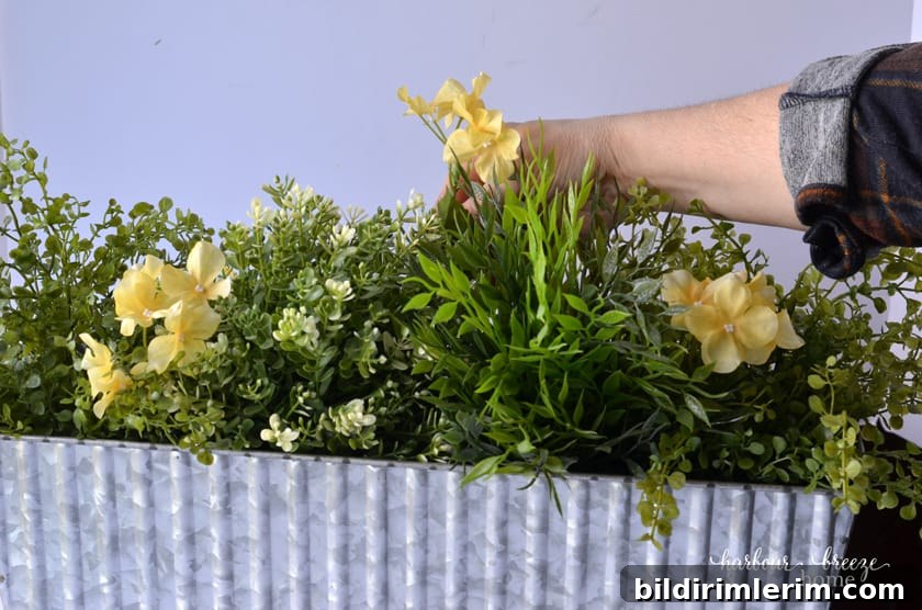 Place yellow flowers interspersed throughout the faux greenery.