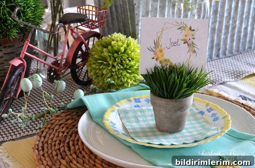 A handwritten place card with the name "Joel" tucked into a faux grass mini potted plant on top of a plate.
