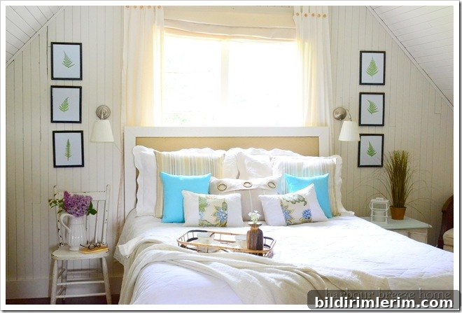A cottage style bedroom with three fern leaf printings hung on either side of the bed on creamy white walls.