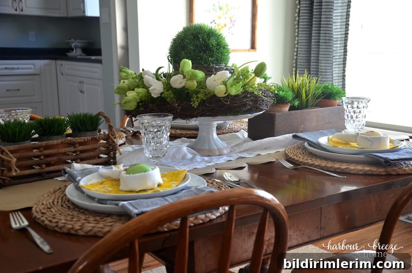 An Easter tablescape featuring bunny ear napkins and faux greenery in the centerpieces of the table.