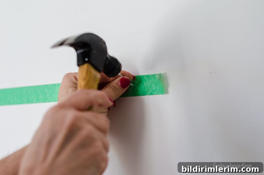 Hang a Picture on Drywall with Two Hooks: Step-by-Step Guide 7 Hammering a nail into the wall for how to hang a picture with two sawtooth hangers.