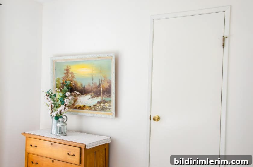 A plain looking wall with a dresser with art above it.