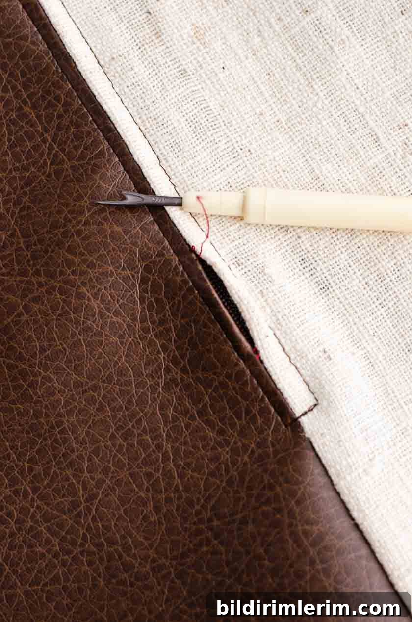Pulling the seam out to reveal the zipper on a faux leather pillow cover.