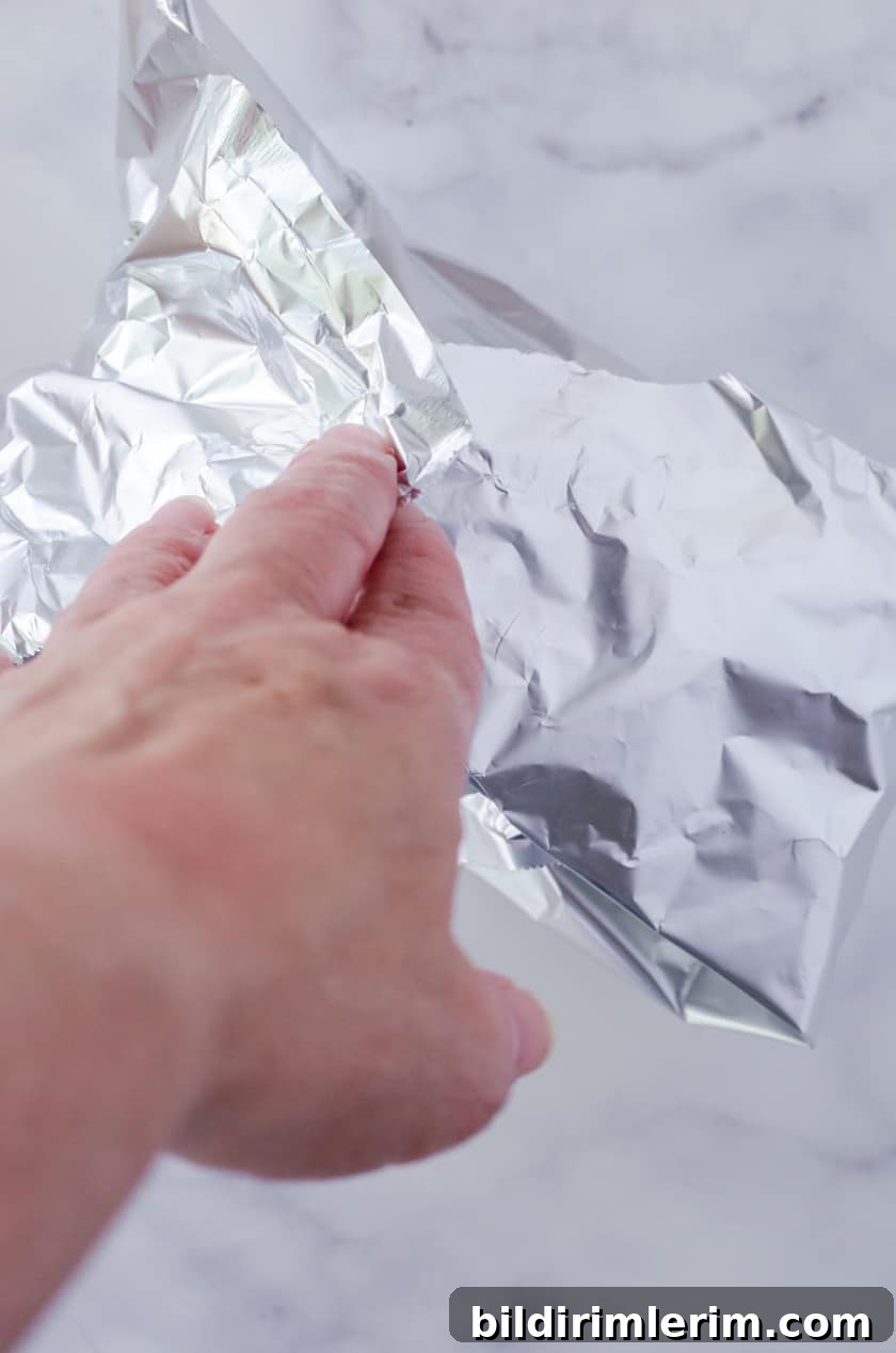 A tuna melt being wrapped in foil before baking