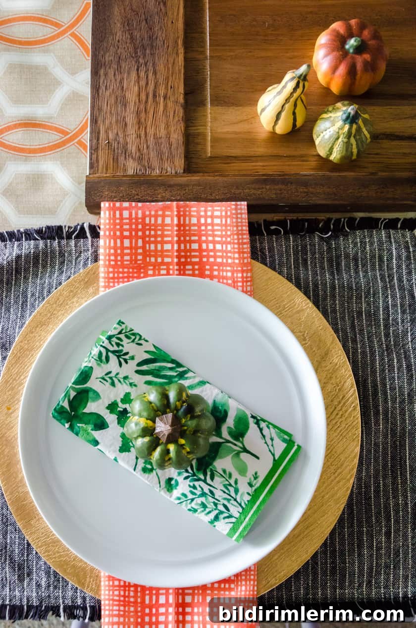 boho style table setting with a faux pumpkin sitting on a green floral napkin on a white plate