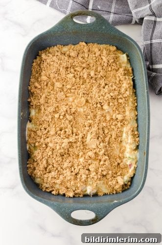coffee cake topping sprinkled on top of rhubarb coffee cake batter in a 9x13 pan