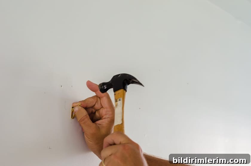 Nailing a picture hook into wall for hanging canvas
