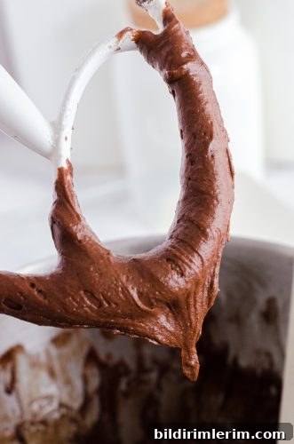 An electric mixer beater with brownie batter on it.