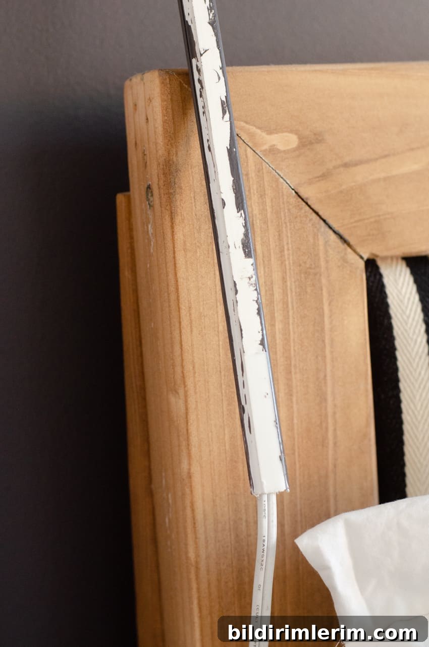 A wall lamp cord cover wrapped around the wall lamp cord with the adhesive back ready to stick to the wall.