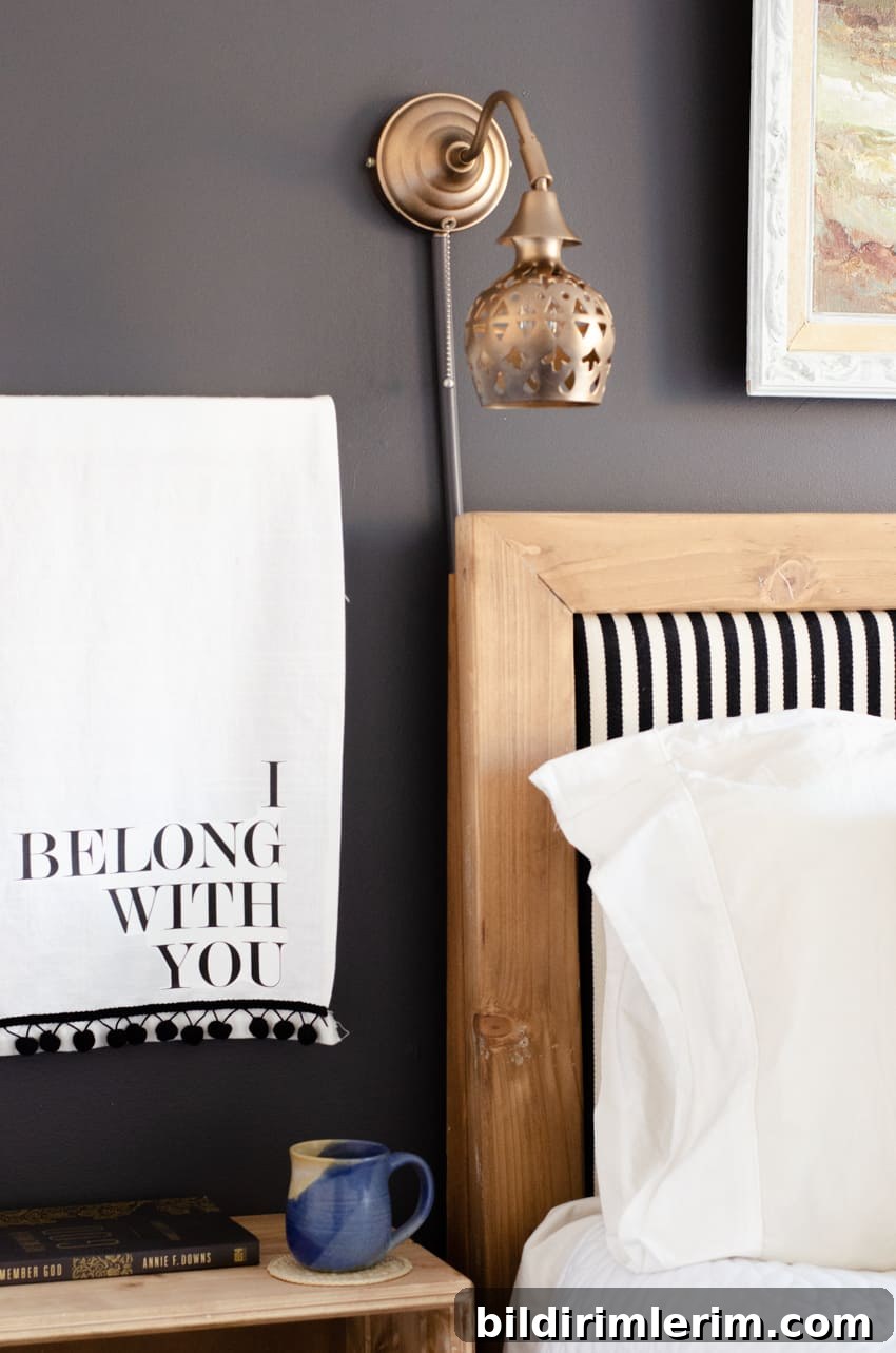A wall lamp cord cover attached to a wall lamp cord above a headboard.