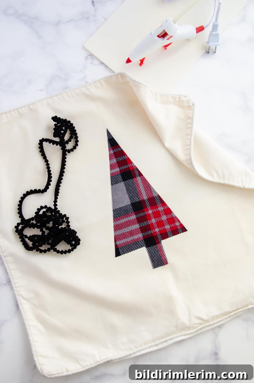 A glue gun can be used to glue on pom pom trim to a DIY Christmas Tree pillow.