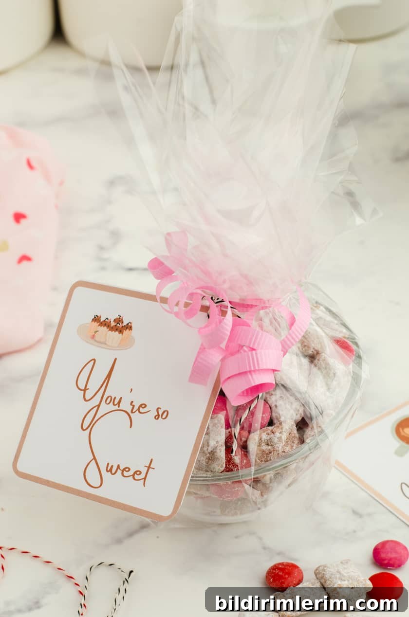 A clear bowl filled with valentines puppy chow mix with clear cellophane wrapped around it and a valentines  tag that says 