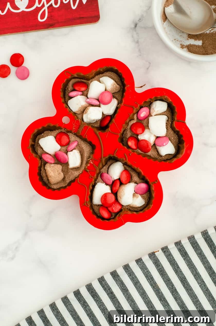 Valentine hot chocolate bombs in heart shaped molds with red and pink m & ms and marshmallows