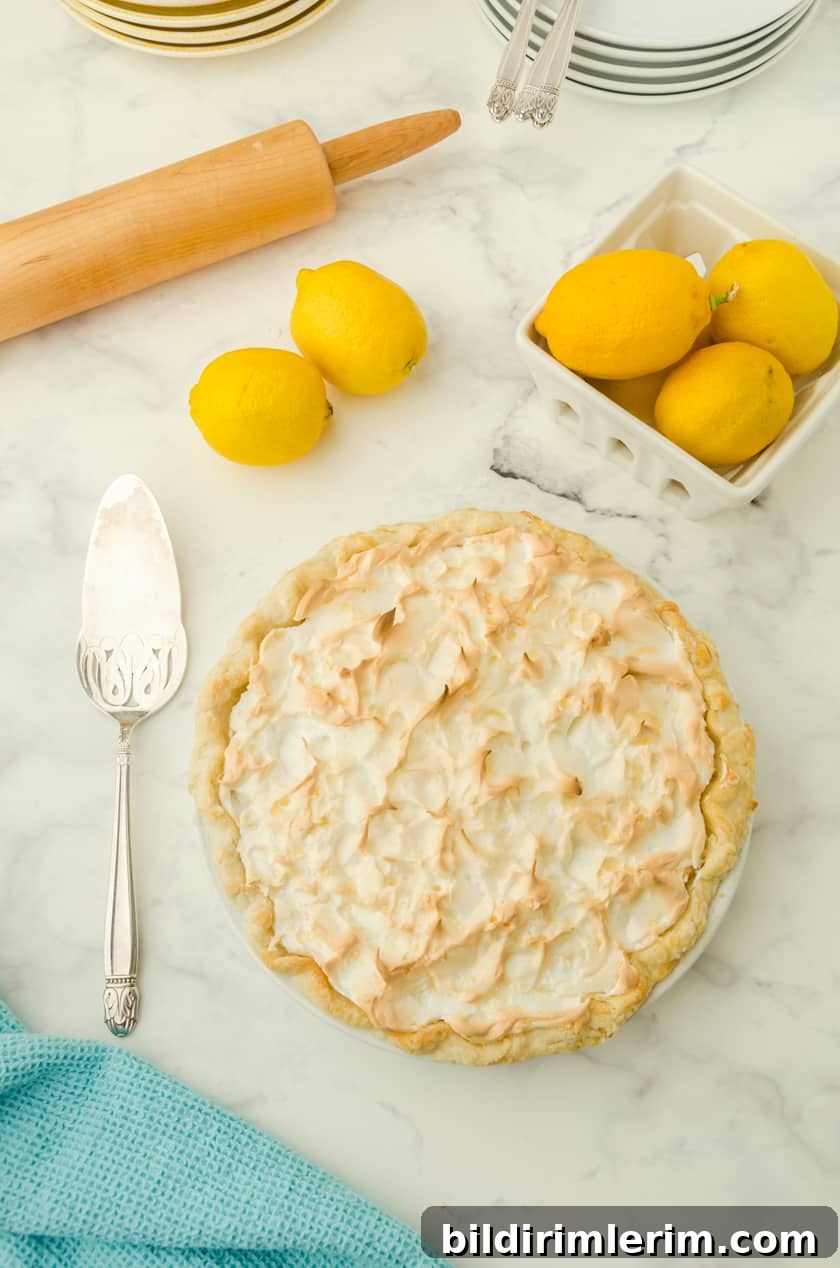 A whole lemon meringue pie with a basket of lemons beside.