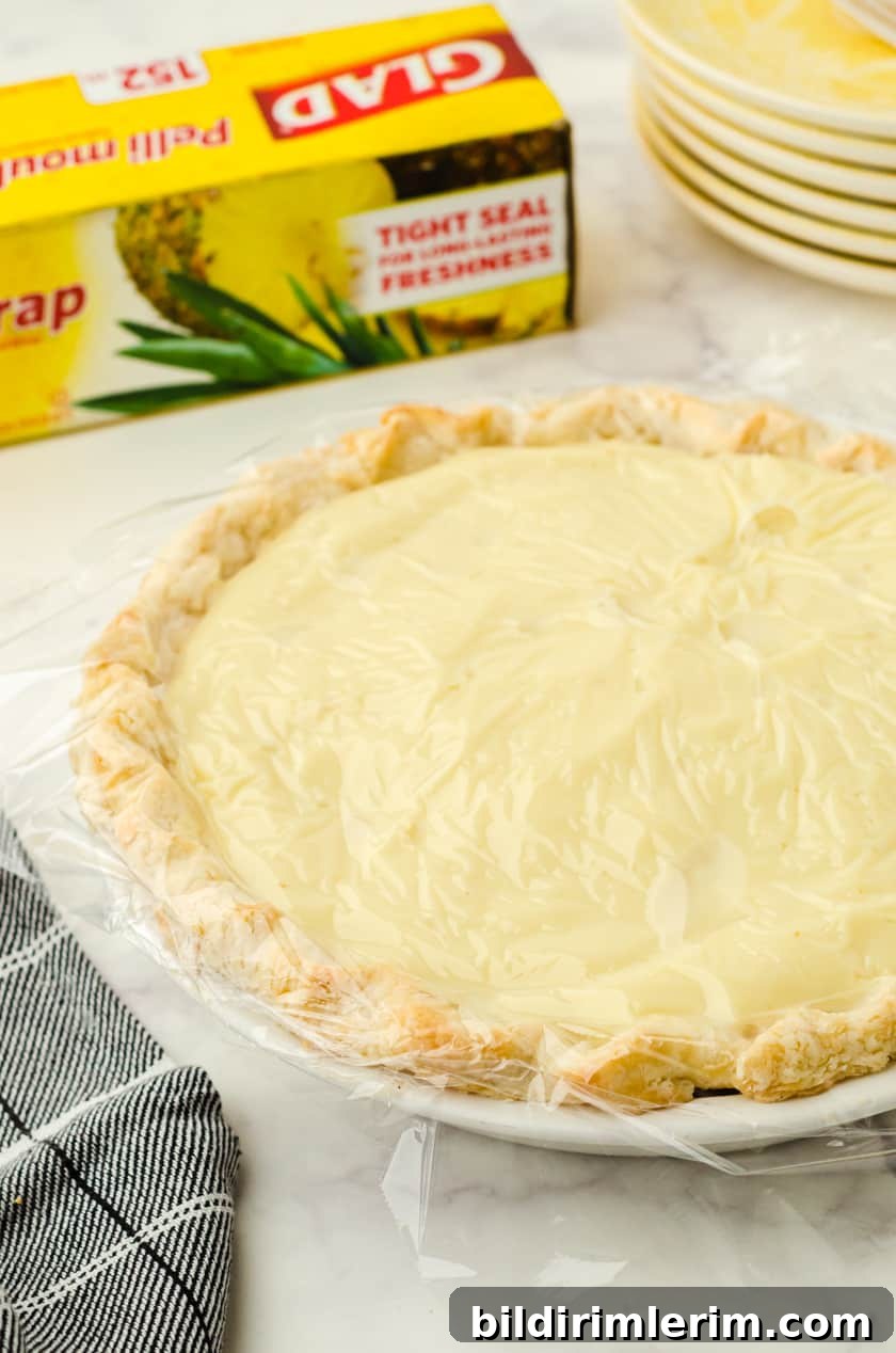 Banana Cream pie with pudding with plastic wrap covering it.