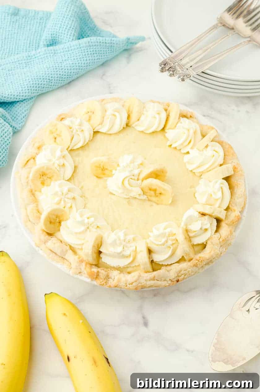 Whole banana cream pie with whipping cream and banana slices on the top