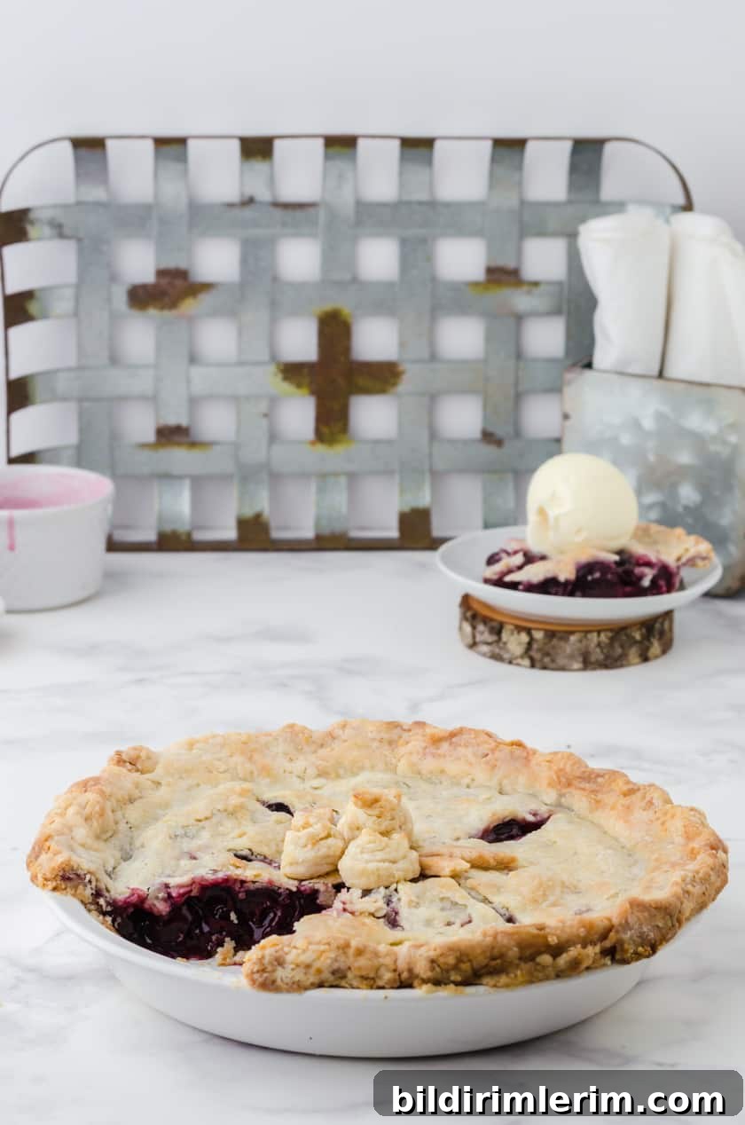 Whole cherry pie with slice out of it.