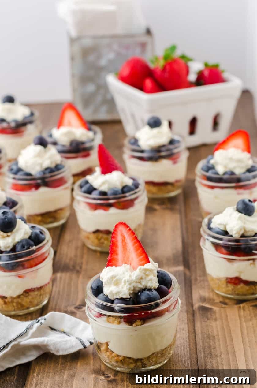 Cheese cake jars sitting on a wooden table with a basket of strawberries behind.