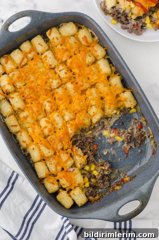 A pan of tater tot casserole recipe with a scoop of it missing.