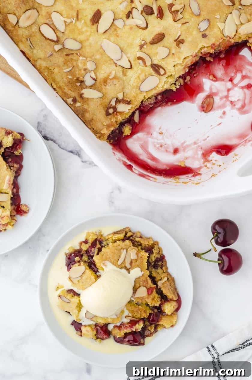 a pan of cherry dump cake with a few servings taken out and a slice of cherry dump cake on a dessert platter with vanilla ice cream melting over the top of it.