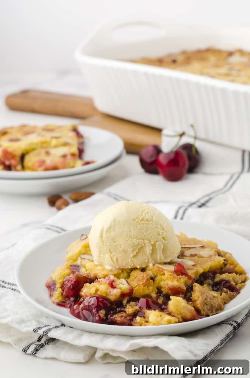 Cherry dump cake on a plate with a scoop of vanilla ice cream on the top
