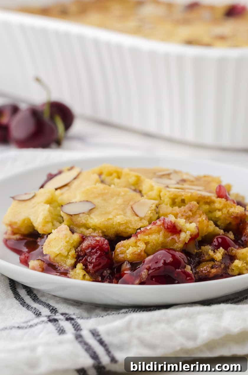 a piece of dump cake with cherries on a dessert plate.