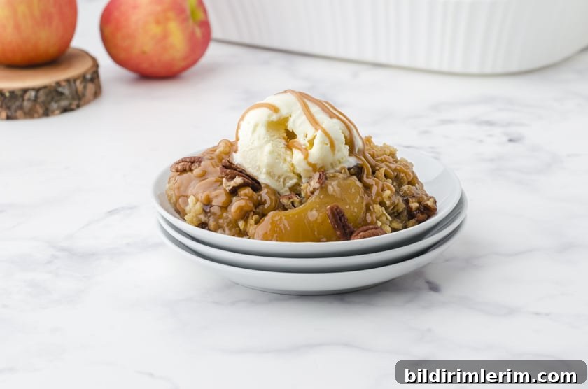 apple crisp with apple pie filling on a plate with ice cream and caramel drizzle