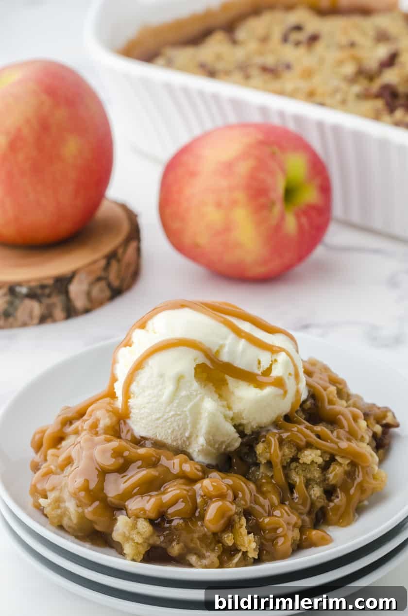 Caramel Apple Crisp dished up with a scoop of ice cream and caramel sauce drizzled over the top.