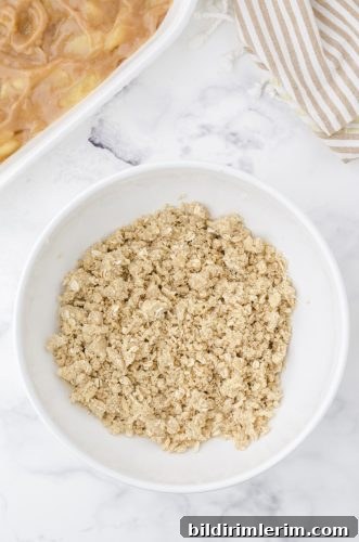 Crumb topping for apple crisp with pie filling in a bowl.