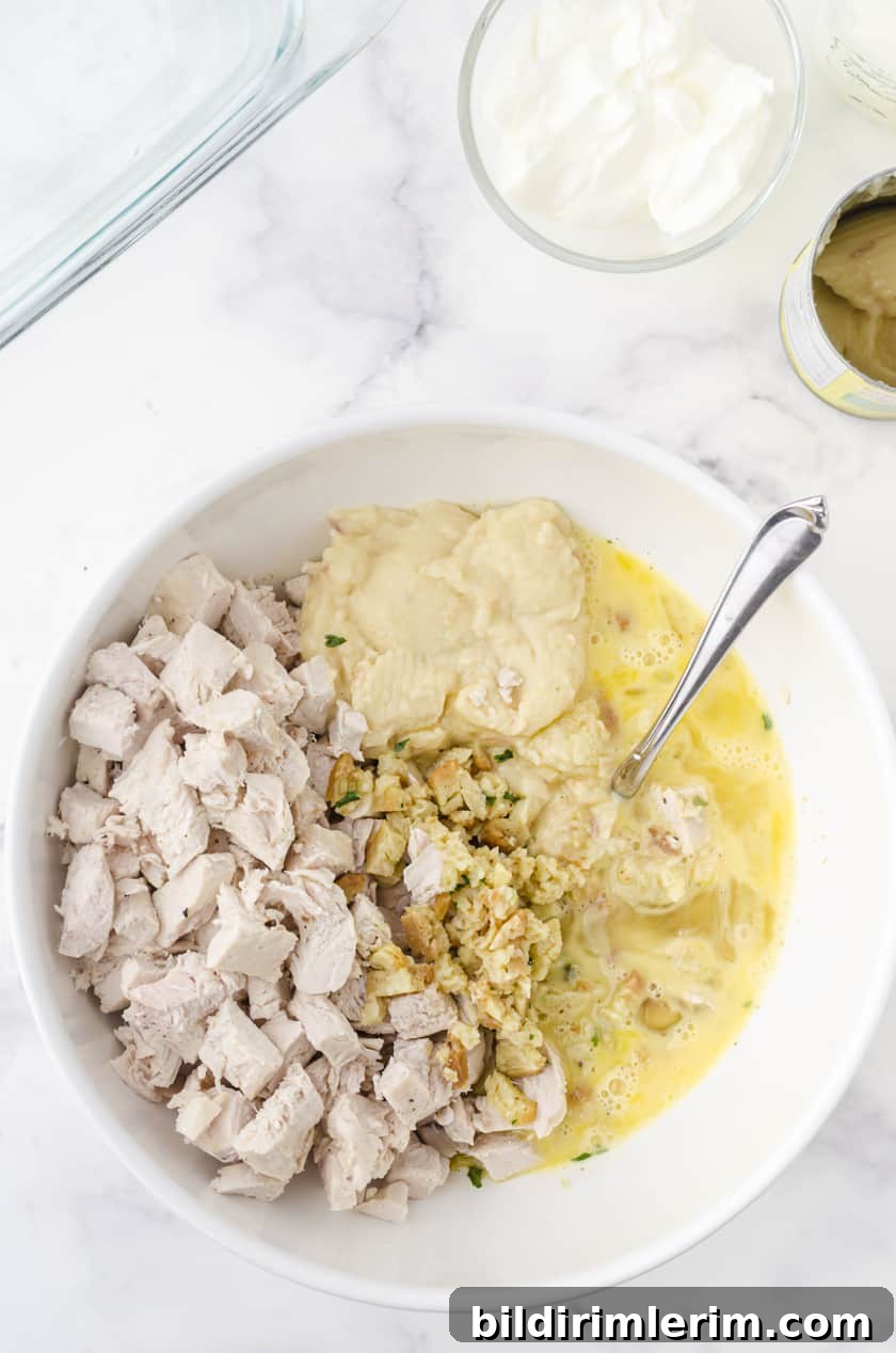 Mixing together ingredients for chicken and stuffing casserole recipe in a mixing bowl.