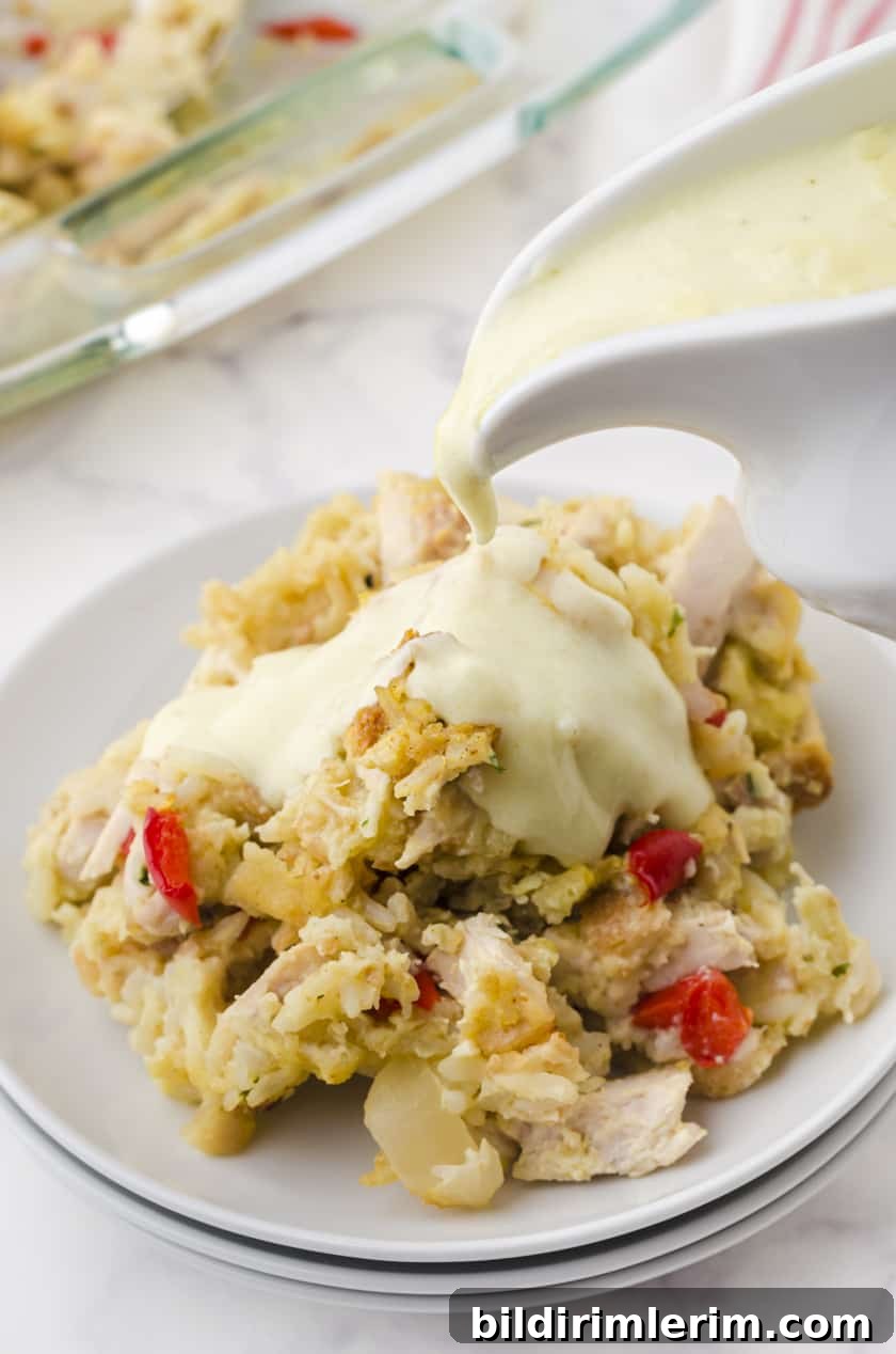 Serving of chicken rice casserole with creamy sauce being poured over it.