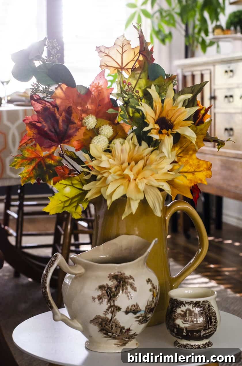 Fall artificial floral arrangement in a sunflower yellow stoneware pitcher.