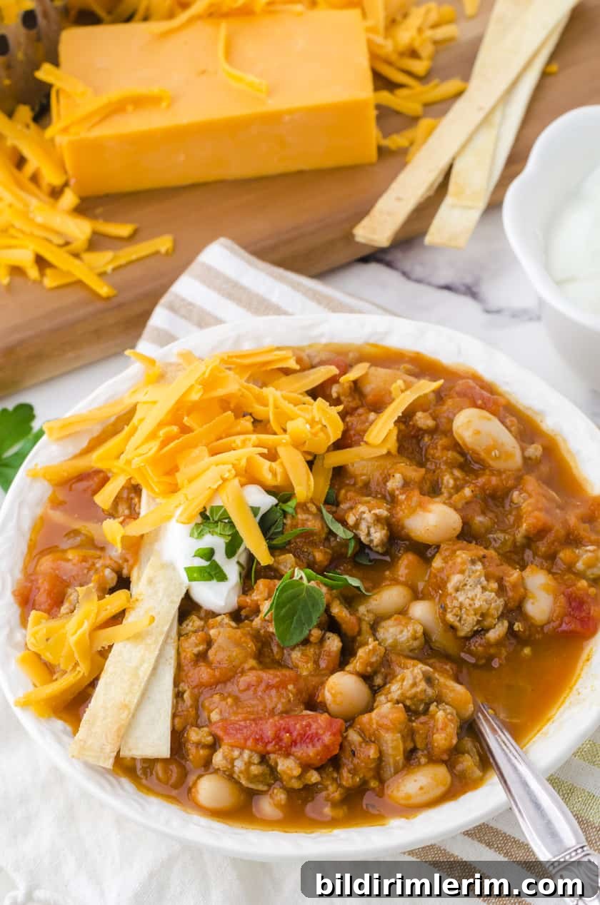 A bowl of turkey pumpkin chili with toppings.