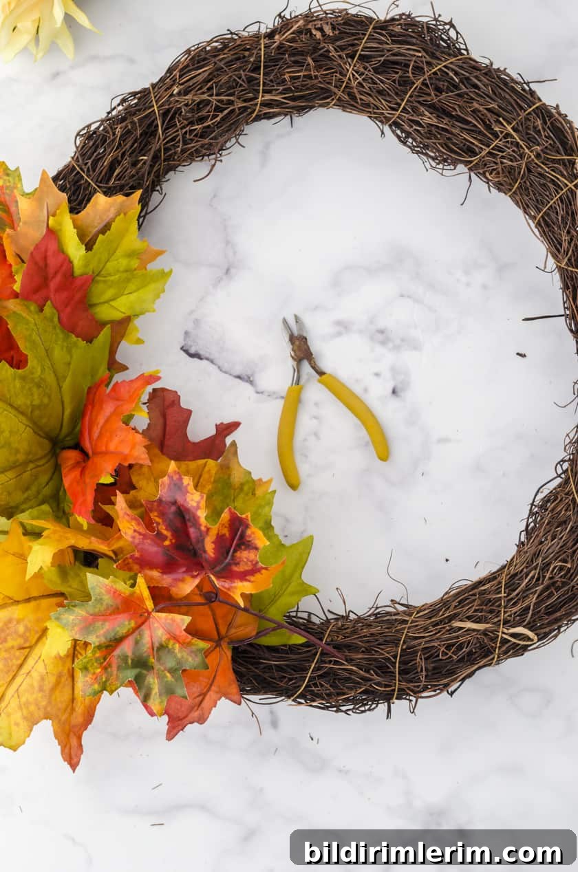 fake leaves being placed into a wreath base for an easy Fall wreath