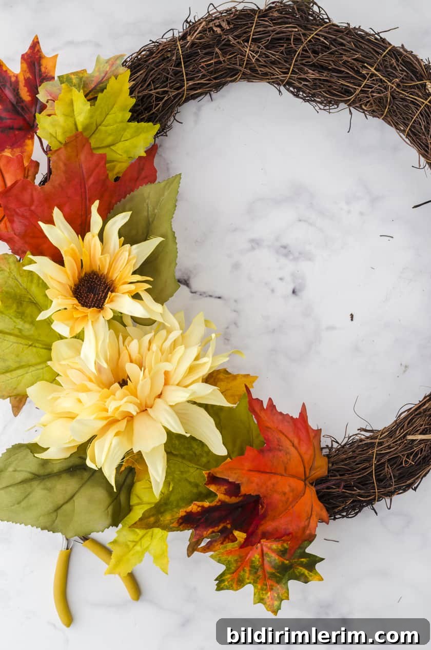 fake flowers and leaves being positioned onto a grapevine wreath base