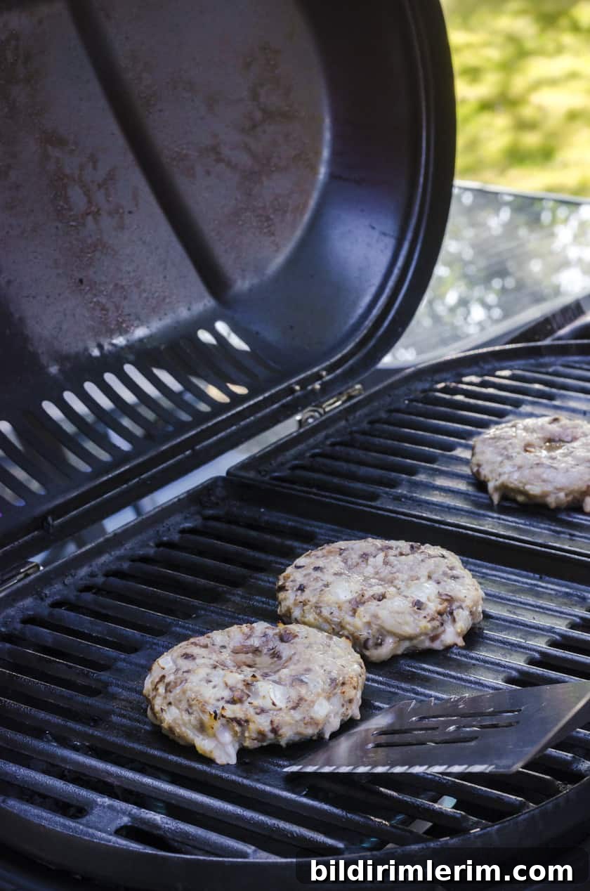 A homemade turkey burger being flipped with a large barbecue flipper.