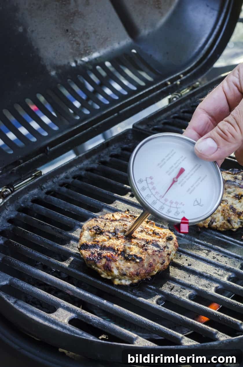 a food thermometer being places in the center of a turkey burger.