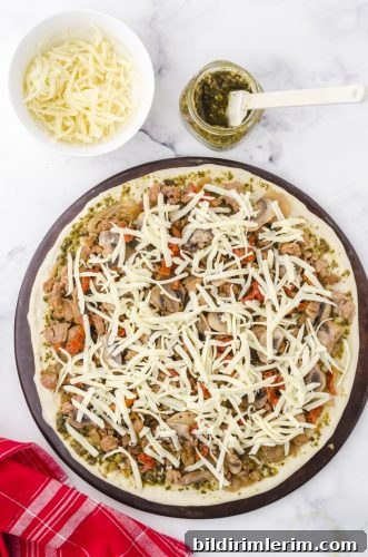 mozzarella cheese layered on a pesto pizza