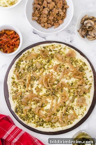 caramelized onions layered over pesto sauce on a pizza crust