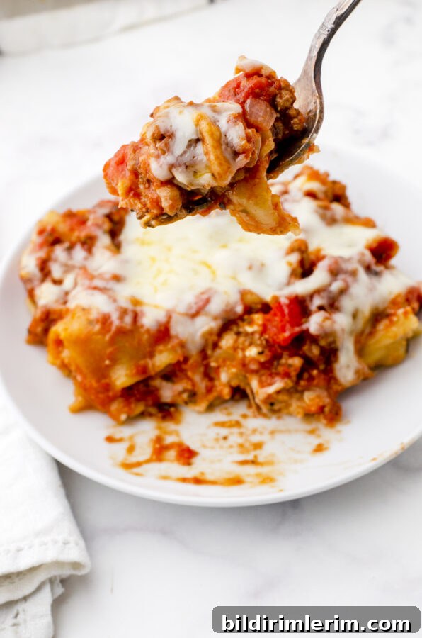 Piece of freeze ahead lasagna cooked and on a dinner plate with a fork holding a bite.