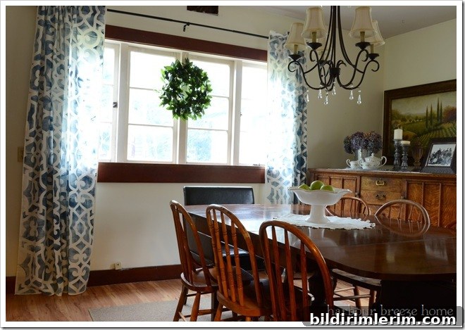 long blue printed curtains hanging in an old farmhouse dining room with wood trim and antique wood furniture
